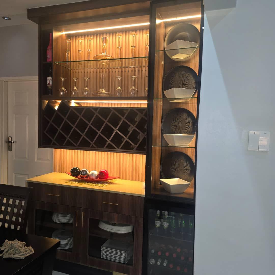 Walnut servery unit with lit glass shelving, a wine rack and an integrated wine fridge.