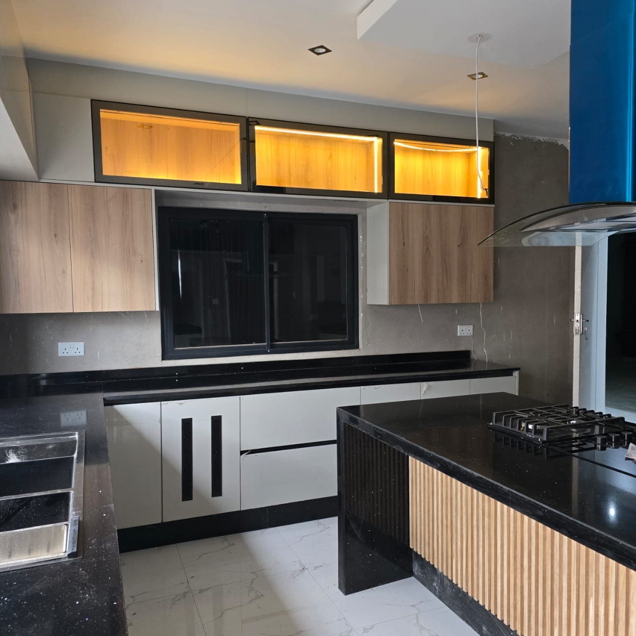 Fitted kitchen with black granite tops, fluted timber island and backlit glass wall units.