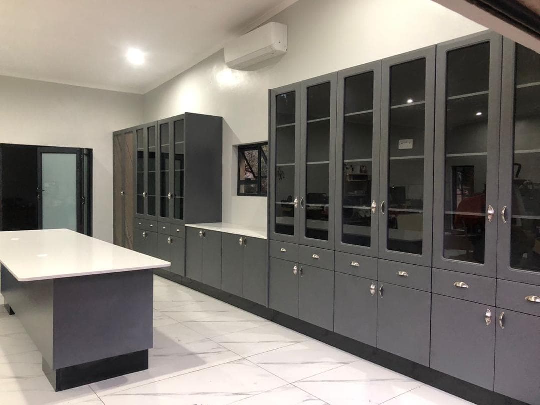 Grey glazed display cabinetry run with a matching island in a commercial interior.