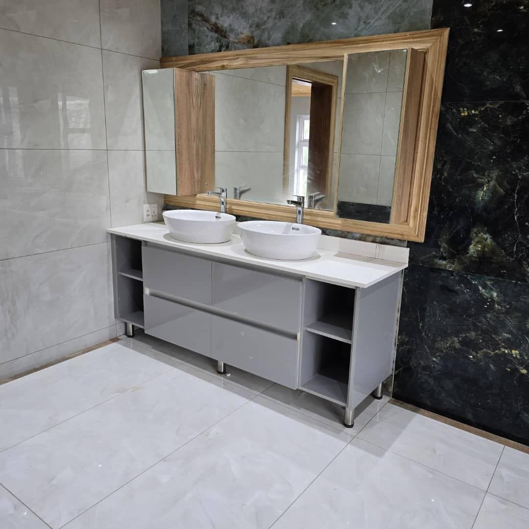 Grey gloss double vanity with twin counter-top basins and an oak-framed mirror.
