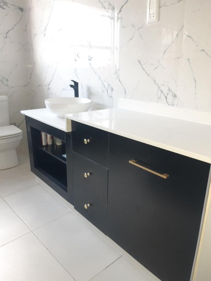 Navy shaker bathroom vanity with a white stone top, vessel basin and brass hardware.